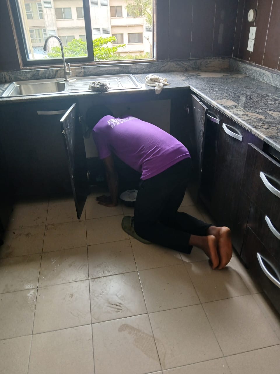Jubilee Pat technician deep-cleaning inside kitchen cabinets